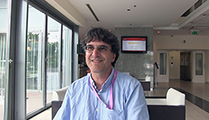 Thumbnail of Alex Vŭlev sitting in a lobby with windows to his right and furniture in the background.