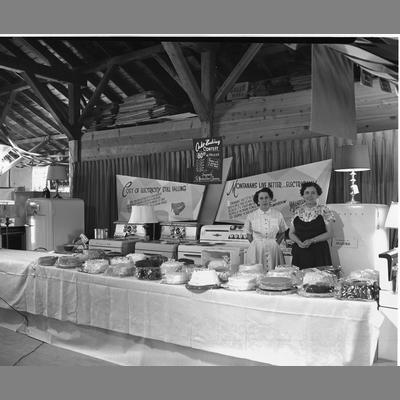 Two women at the Montana Power Booth at the Madison County Fair, 1955.