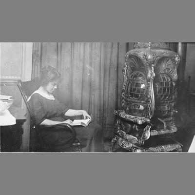 A Woman Reading, Sitting Next to a Wood Stove