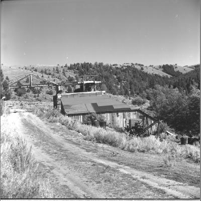 Abandoned Frame Structure Next to Dirt Road With What Appears to be a Railroad Bridge, August 1959
