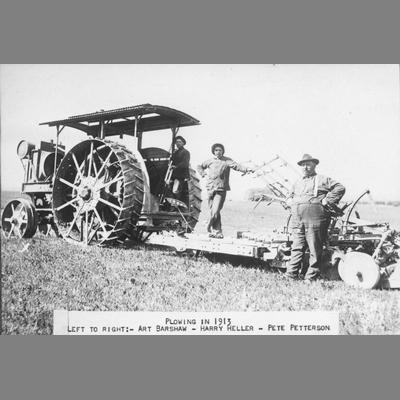Plowing - Three farmers pose next to large steel-wheeled tractor, 1913.