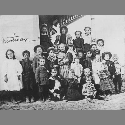 Group of children and adult women posing during the Newell Party, circa 1900.