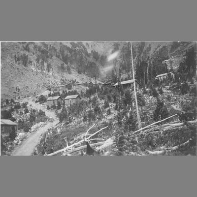 Dirt Road Winding Through Scattered Cabins on Mountain Canyon