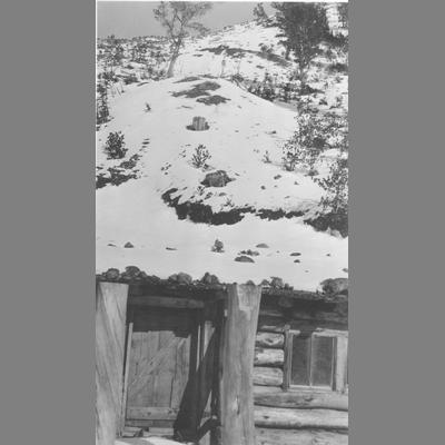 Close Up View of Front Door of Snow Covered Log Cabin Dugout