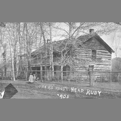 Woman and Boy Stand in Front of the Robbers Roost a Two Story Log Cabin 1905