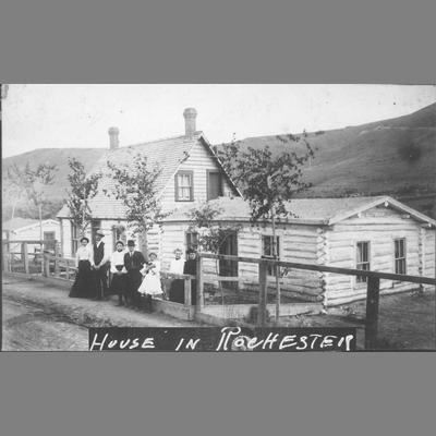 Family posing in front of log residence in Rochester, Montana, 1890.