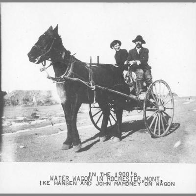 Ike Hansen and John Mahoney riding in water wagon pulled by one horse, circa 1900.