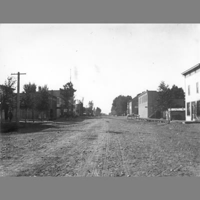 Head On View of Dirt Main Street Flanked by Business Structures
