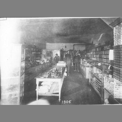 Three Men Stand in Rear of Twin Bridge's Dry Goods Store