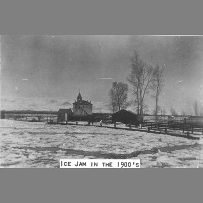 Tall school building with ice and water spreadout in foreground, circa 1900s.