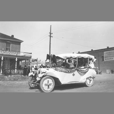 Red Cross Costumes Worn by Riders in a Decorated Car Driving Along Main Street