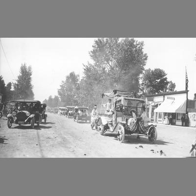 Rear View of Decorated Automobiles Moving Down Dirt Road in Twin Bridges Parade circa 1920
