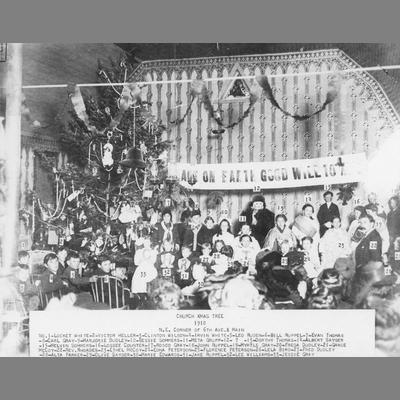 Group poses in front of church Christmas tree, 1910.