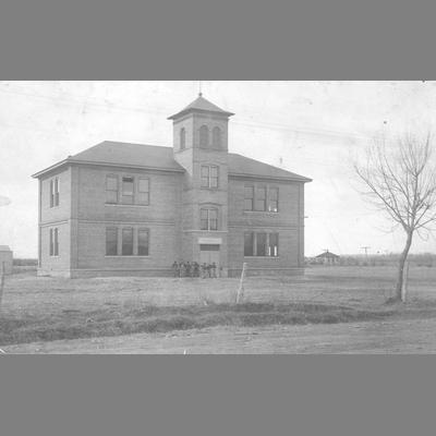 Distant View of Large Brick School Building With Boys in Front
