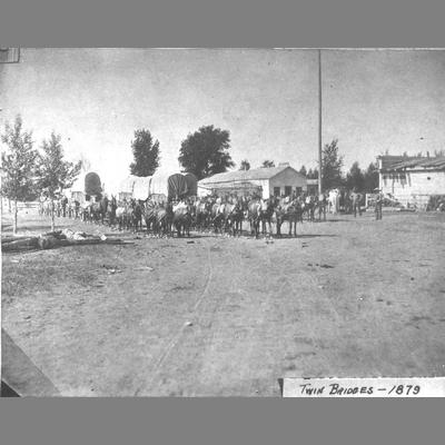 Several Covered horse-drawn Wagons on Dirt Road Passing in Twin Bridges, Montana, 1879