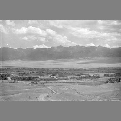 Tree Lined River Running Through an Open Valley with Mountains Visible