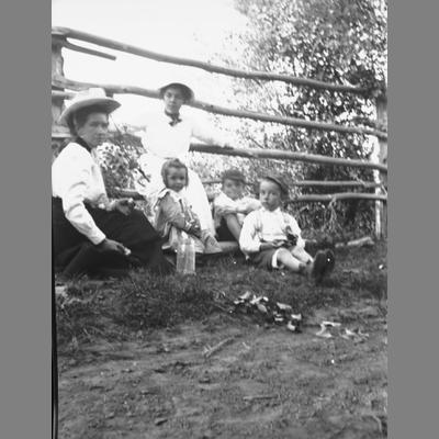 Two women pose with three children next to a fence.