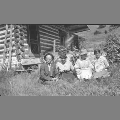 A Man and Three Women Sit in Front Yard Displaying a Portrait
