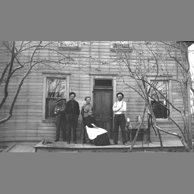 Five unidentified individuals pose outside a door on a porch.