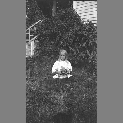 Little Girl Sits in Yard with Teddy Bear in Lap