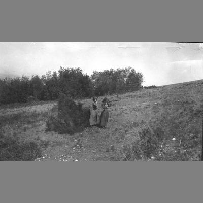 Two Pioneer Women Firing a Gun in a Field