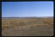 Wire fence with field and benchlands behind