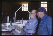 Ivan Doig and Bob Facklam study machinery at Teton Welding in Choteau