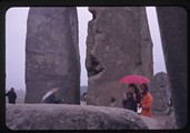 People walk about Stonehenge in the rain
