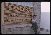 Carol Doig leaning against Ekalaka, Montana sign