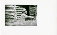 Ivan Doig sitting in the grass at D.L. Doig homestead - black & white looking up