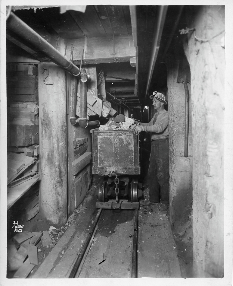 Miner working with mine cart loaded with rocks