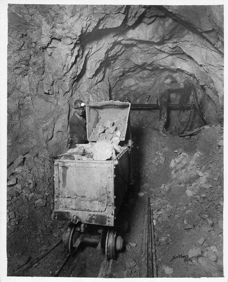 Butte miners working with mine carts loaded with rock