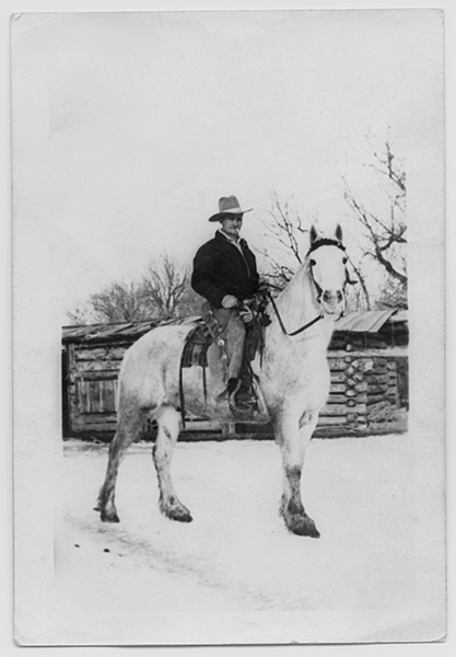 Man on Horse in Front of Log Cabin, Unknown Location