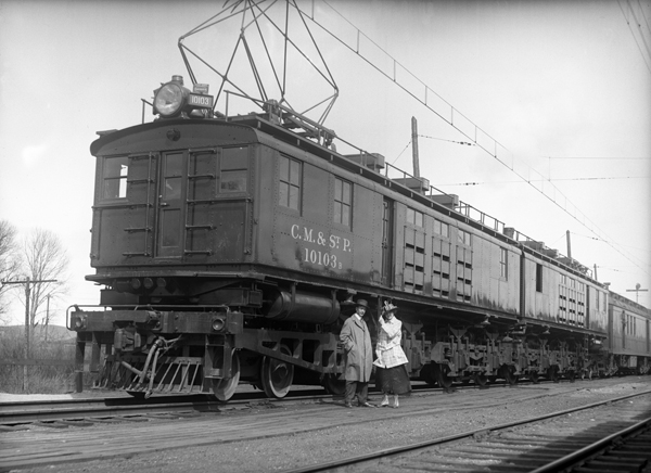 Man and Woman In Front Of Electric Locomotive Engine, Harlowton, Montana