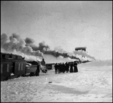 NP trains stalled in snow storm on Dak Divn about 1913  cy  D S Colby  Some of the men standing in the snow appear to be wearing trainmen's hats  The women may be passengers  There appears to be a coal dock in the background  The old Dakota Division stretched from Fargo to Mandan, and included several branch lines