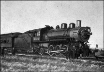 NP 2422, Prairie Type, Class T, 2-6-2, view mostly of locomotive and a few dressed up people close to the locomotive pulling one coach that is in view, at Hesper MT.  Several folks are off the train and posing for the camera.  