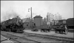 NP 2203, Pacific type, Class Q-4 in Spokane, WA, as it arrives double headed.  Baggage man waiting for train to stop.