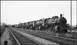 String of new USSR steam locomotives in Portland, OR, boarded up for possible shipping to USSR.  Locomotives only, no tenders connected.