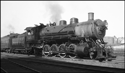 A very clean class W 2-8-2, built by Alco in 1905 at their Brooks works, normally a freight engine, on a passenger train.  Truss rod coach behind engine.  Perhaps this is a special excursion train?