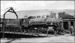 NP 33, Class Y locomotive on turntable at Missoula, being handled by NP 138 DE switcher.  Missoula roundhouse in background.