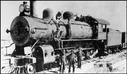 Grimy NP 4-6-0 compound Ten-Wheeler no. 136 and crew stand for a portrait at Grass Valley, MT.