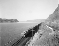 A handsome Union Pacific caboose decorates the rear of an eastbound freight rolling up the Columbia River near Umatilla, OR.