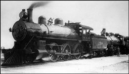 NP 258, Class P locomotive coupled onto the head end of another steam locomotive, with several workman along side locomotives.