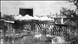 NP passenger Extra doubled headed with NP 2457, Class T-1 and NP 2150, Class Q-3 crossing Mississippi river between Minneapolis and St Paul on NP bridge.  Baggage car at back of train.