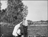 Ron Nixon's parents standing on rocks in possibly the Boulder River at Big Timber, judging from width.