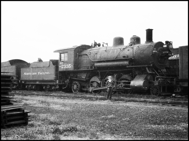 A young man poses with NP 2335, a 2-6-2 Prairie Class T, at Northtown, Minnesota.