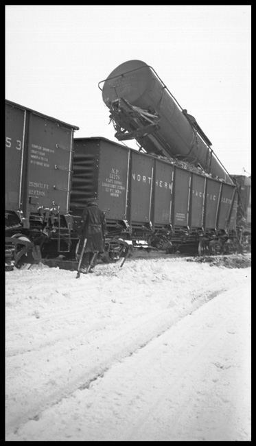 Tank car on end in gondola after Two Class Z-6 locomotives NP 5102 and NP 5018 collided at Muir, MT.  NP X5102W was standing on West track at Muir when X5108E doubling through tunnel could not automatically operate frozen switch from West End, and was unable to stop coming out of tunnel colliding with NP 5102.