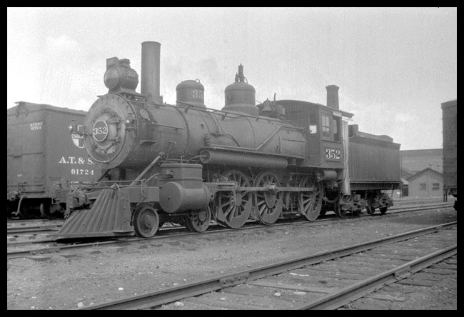 NP 352, Class E-3 photographed in Livingston yard near wheel shop.  Old stationary stack in background.