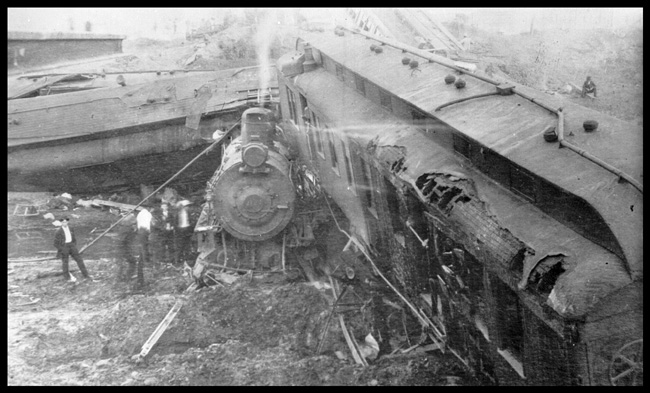 Distant view of passenger train pulled by NP 2128, Class Q-1 wrecked at Allard, MT in November 1908. Many by-standers watching after the accident.  Four were killed and 20 injured.  Fire damage in coach is shown in the view from high up.
