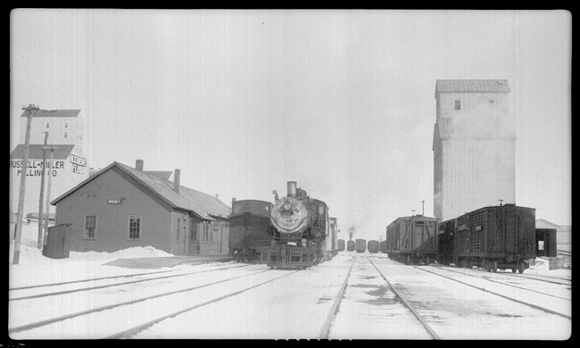 Station at Sidney, MT.  Two engines in yard and snow and Ice on the ground.